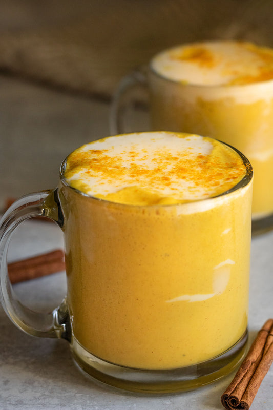 A frothy bright yellow cup of Golden Milk, made with Gathering Place Turmeric Powder
